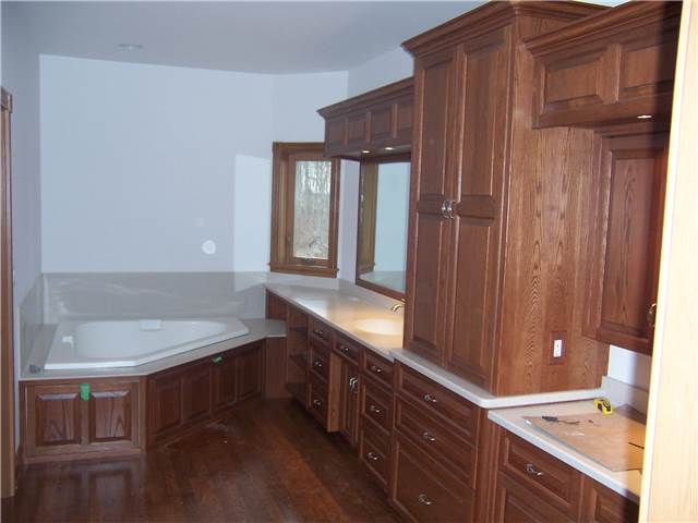 Red oak cabinets - Raised panel doors, drawer fronts, and tub access panels - Full overlay style - Corian solid surface countertops with integral sinks - Corian tub deck and backsplash
